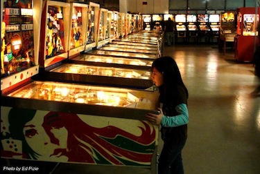 Young girl playing an old pinball machine